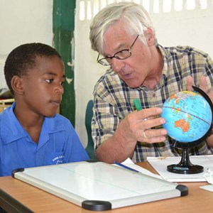 Volunteer from Global Volunteers teaching geography to a student