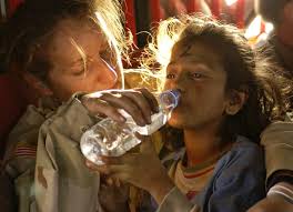 volunteer giving child clean drinking water